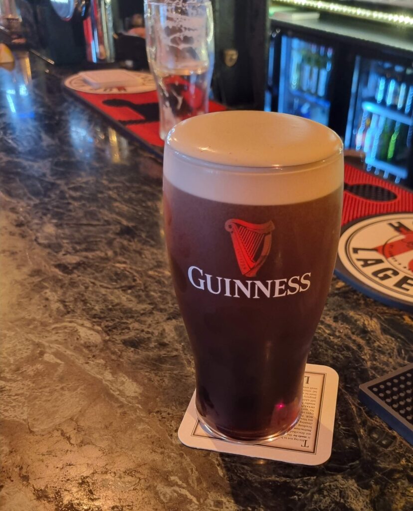 Pint de cerveja stout preta da marca Guinness em um pub tradicional na Irlanda, simbolizando a origem do blog Turismo Sem Fronteiras.