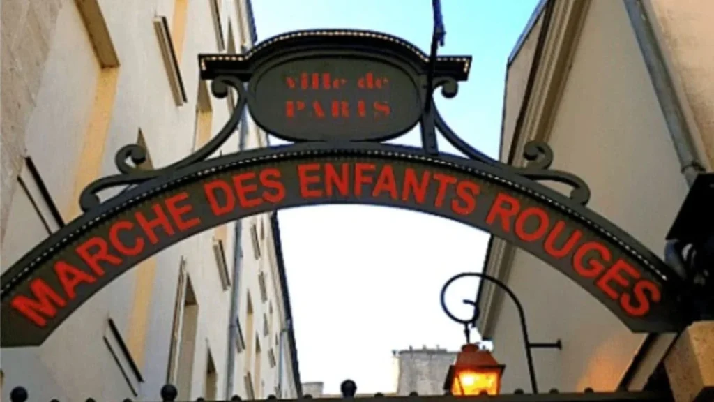 Placa de ferro arqueada na entrada do Marché des Enfants Rouges em Paris, indicando um mercado histórico de gastronomia acessível.