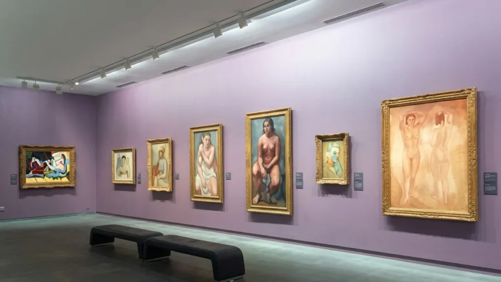 Galeria de arte com paredes em tom lilás vibrante exibindo diversas pinturas clássicas em molduras douradas da Coleção Jean Walter e Paul Guillaume no Museu de l'Orangerie. Bancos pretos de couro no centro.