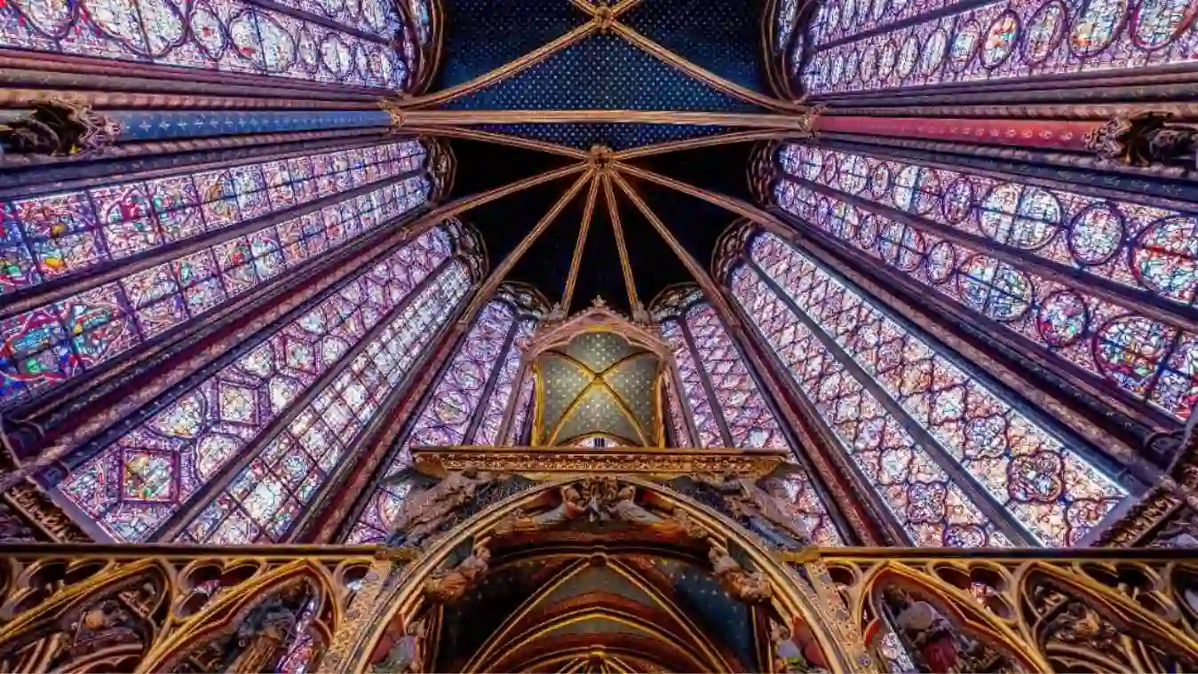 Interior da Sainte-Chapelle em Paris com foco nos vitrais coloridos do século XIII e teto estrelado durante um roteiro a pé.